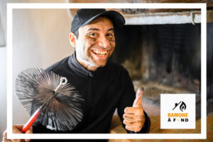 Un ramoneur souriant, le visage marqué de suie, tenant une brosse de ramonage devant une cheminée propre, illustrant l'importance du nettoyage printanier des conduits.